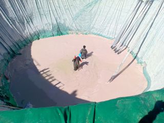 Two rare earth miners stand at the bottom of a leaching pool in Kachin State, Myanmar