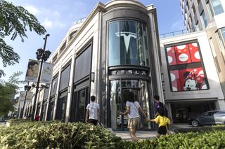 People walk past a Tesla dealership in Shanghai, China